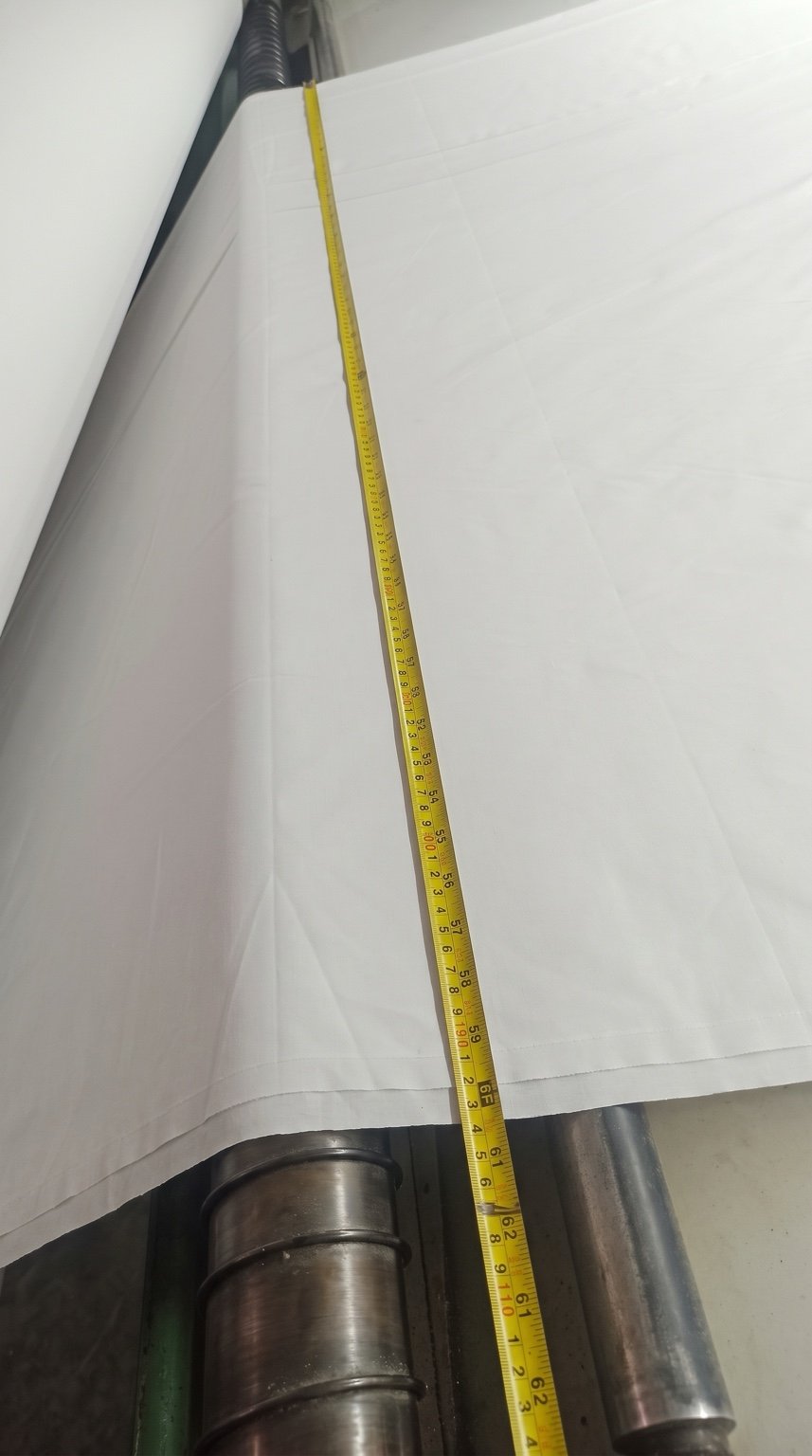 Measuring tape placed across white fabric during a width check